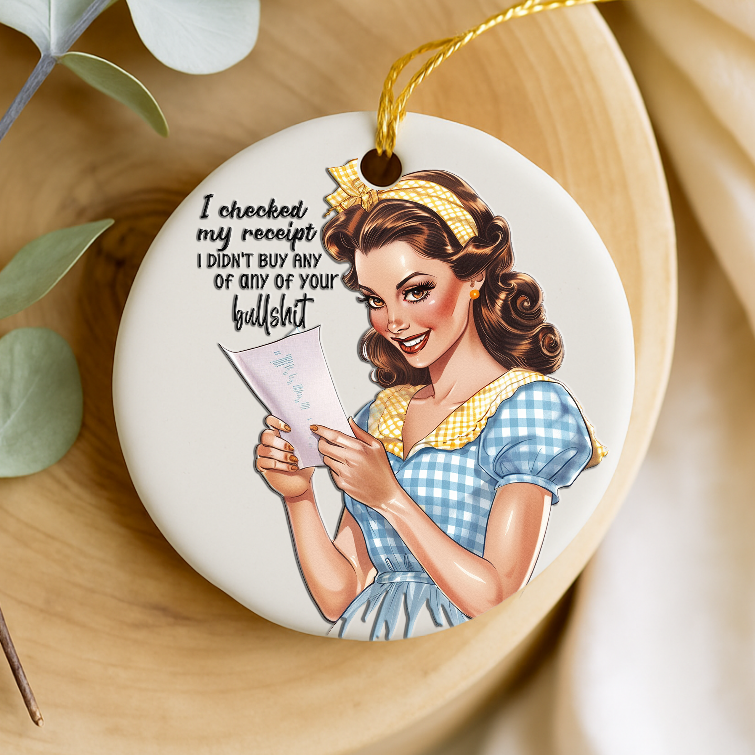 Decorative keepsake with a vintage-style illustration of a woman holding a receipt, placed on a wooden surface with a leafy branch.
