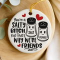 Decorative porcelain keepsake with salt and pepper shakers and humorous text on a wooden surface.
